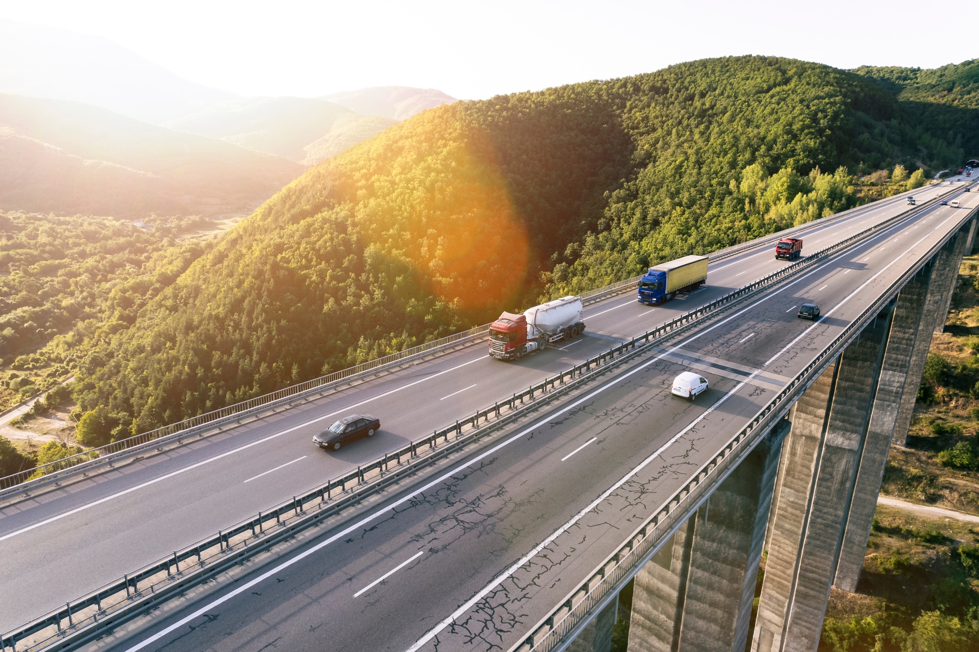 Aerial drone view of busy highway viaduct bridge with many cargo transportation trucks driving on